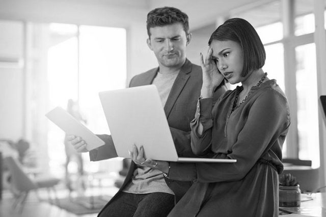 Coworkers viewing laptop, upset about data loss from human error